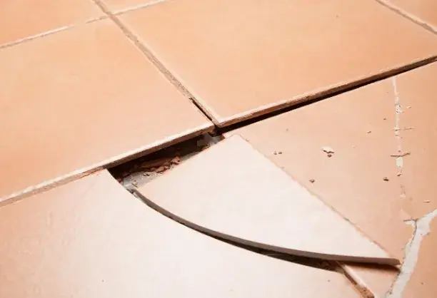 Baldosa de suelo agrietada y levantada en un pasillo antes de la reparación