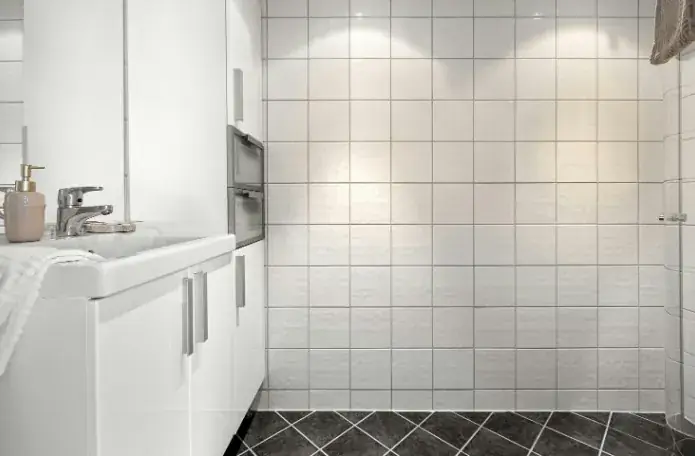 Baño con alicatado blanco y juntas bien selladas tras el mantenimiento en Huelva