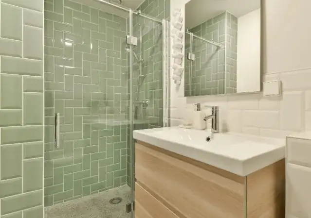 Baño reformado con alicatado verde y mueble de madera en Huelva