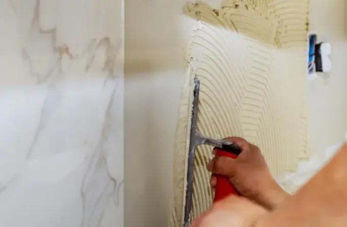Aplicación de cemento cola con llana para revestimiento de pared con porcelánico en Huelva