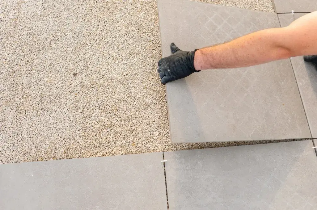 Colocación de losas de gres sobre base de grava en pavimentación de jardín en Huelva